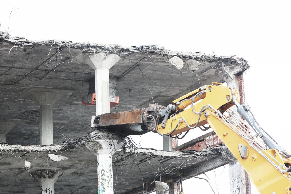 Abbruchgreifer beißt in eine Betondecke, die Bewehrung liegt frei